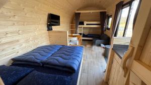 a bedroom with a large blue bed in a tiny house at Aqua Lodge in Petten +14 photos