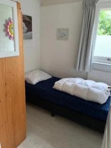 a bedroom with a bed with two pillows and a window at Bungalow 001 in Petten