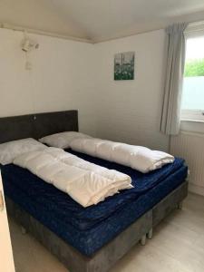 a bed with pillows on it in a bedroom at Bungalow 001 in Petten +9 photos