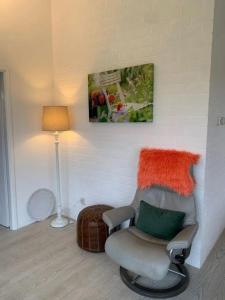 a living room with a chair and a lamp at Bungalow 001 in Petten