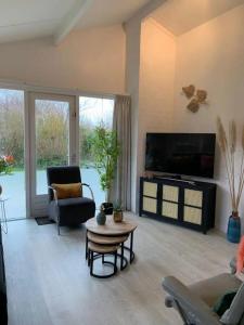 a living room with a tv and a couch and a table at Bungalow 001 in Petten