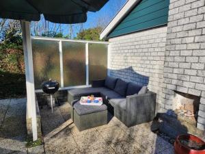 a patio with a couch and chairs and an umbrella at Bungalow 002 in Petten