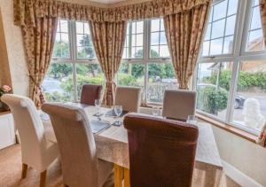 a dining room with a table with chairs and windows at Rose-Fitt House in Hunstanton