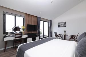 a bedroom with a bed and a desk with a television at Charm Champion Villa Hoian in Hoi An