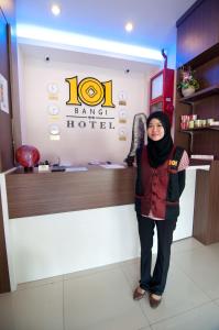 a woman standing in front of a barber shop at 101 Hotel Bangi in Bangi