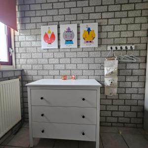 a white dresser with four pictures on a brick wall at Bungalow 017 in Petten +7 photos