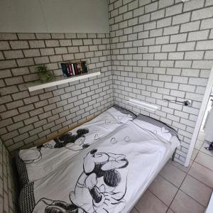 a bed in a corner of a brick wall at Bungalow 017 in Petten