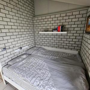 a bed in a room with a brick wall at Bungalow 017 in Petten