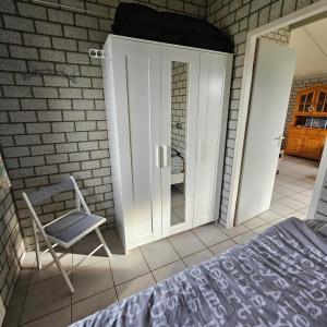 a bedroom with a bed and a chair next to a door at Bungalow 017 in Petten