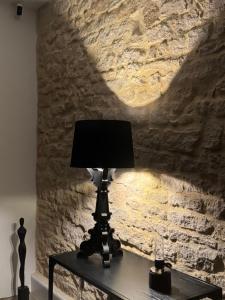 a lamp on a table in front of a stone wall at La suite du parc 1 in Nancy
