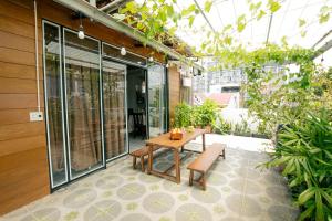 a patio with a table and benches and a greenhouse at Rustic Homestay Bình Dương in Phú Lợi