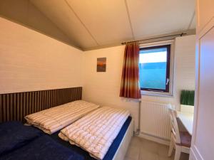 a bedroom with a bed and a desk and a window at Bungalow 028 in Petten +6 photos