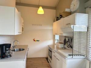 a kitchen with white cabinets and a sink at Bungalow 027 in Petten
