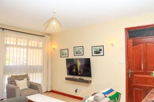 a living room with a tv on a wall at Madiniplace 1 - Flexible 1-3BR Apartment near JKIA & SGR in Nairobi