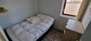 a white bed in a room with a window at Bungalow 038 in Petten
