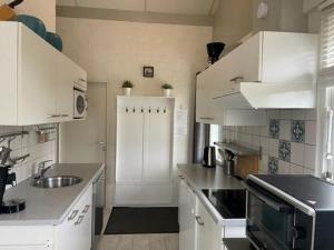 a kitchen with white cabinets and a sink at Bungalow 040 in Petten