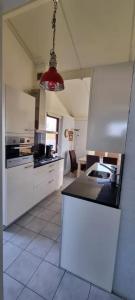 a kitchen with white cabinets and a black counter top at Bungalow 038 in Petten