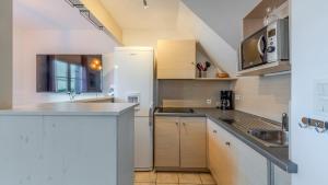 a kitchen with white cabinets and a white refrigerator at T de Pentrez N58 3P4 in Saint-Nic