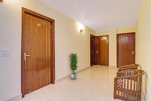 a hallway with wooden doors and a potted plant at Hotel O Premnagar Heights in Jhājra