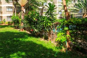 a yard with trees and plants in front of a building at Madiniplace 1 - Flexible 1-3BR Apartment near JKIA & SGR in Nairobi