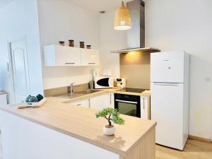 a kitchen with a counter and a white refrigerator at Le Thieblemont - Elegance and Private Outdoor Space in La Chapelle-Saint-Luc