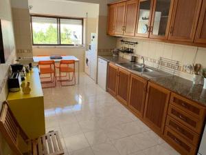 Una cocina grande con gabinetes de madera y sillas naranjas. en Canto Simples Rose, en Nazaré