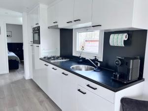 a white kitchen with a sink and a window at Chalet 5 in Petten