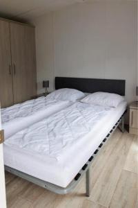ein großes weißes Bett in einem Zimmer mit Holzboden in der Unterkunft J 009 in Petten