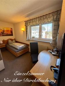 a hotel room with a bed and a desk and a window at Pension Weißer Hirsch in Schwarzenberg (Erzgebirge)