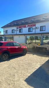 a red car parked in front of a building at Hotel Poem in Călăraşi