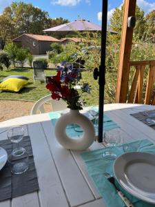 a table with a vase with flowers on it at CHALET 10 chaleureux tout confort dans domaine avec Piscine au cœur des Landes bord de Lac avec plage aménagée in Labouheyre