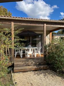 a patio with a table and chairs and an umbrella at CHALET 10 chaleureux tout confort dans domaine avec Piscine au cœur des Landes bord de Lac avec plage aménagée in Labouheyre