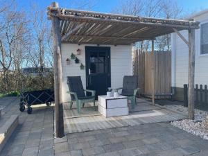 eine Pergola mit zwei Stühlen und einem Tisch auf einer Terrasse in der Unterkunft J 013 in Petten