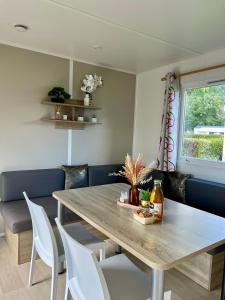 Un comedor con una mesa y sillas blancas. en Mobil home spacieux 5 personnes à 15 min de Concarneau, en Trégunc