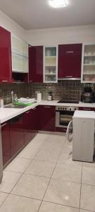 a kitchen with red cabinets and a white tile floor at Art house M & F in Órion
