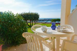 a white table and chairs on a patio with the ocean at Appartement en rdc - résidence la Goëlette Port Bourgenay - 4 personnes in Saint-Jean-dʼOrbetiers
