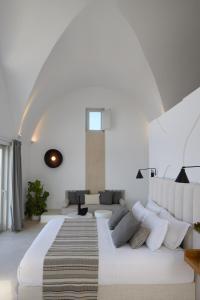 a white bedroom with a large bed and a couch at Omna Caldera Suites in Akrotiri +141 photos