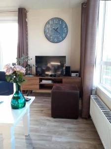 ein Wohnzimmer mit einer großen Uhr an der Wand in der Unterkunft J 019 in Petten