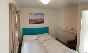ein kleines Schlafzimmer mit einem Bett mit blauem Kopfteil in der Unterkunft J 020 in Petten