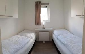 zwei Betten in einem Zimmer mit Waschbecken und Fenster in der Unterkunft J 020 in Petten