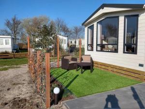 ein kleiner Hinterhof mit einer Terrasse mit grünem Gras in der Unterkunft J 019 in Petten