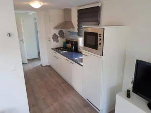 eine Küche mit weißen Schränken und einer Mikrowelle in der Unterkunft J 020 in Petten