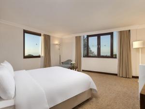 a hotel room with a white bed and windows at Rixos Park Belek - The Land Of Legends Access in Belek +169 photos