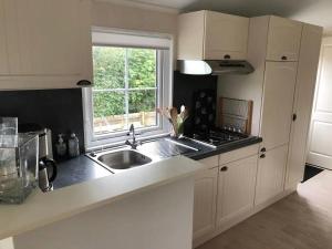 eine weiße Küche mit Spüle und Fenster in der Unterkunft J 059 in Petten