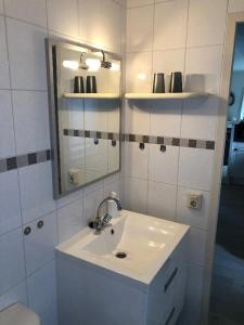 ein weißes Badezimmer mit Waschbecken und Spiegel in der Unterkunft J 059 in Petten