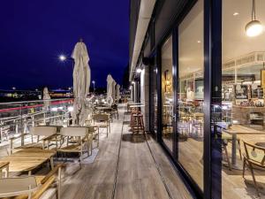 ein Restaurant mit Tischen und Stühlen auf einem Balkon in der Nacht in der Unterkunft ibis Styles Paignton in Paignton