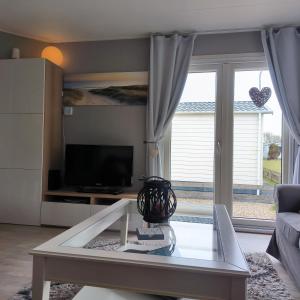 ein Wohnzimmer mit einem Couchtisch aus Glas und einem Fernseher in der Unterkunft J 062 in Petten + 12 Fotos