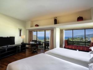a hotel room with a bed and a television at Pullman Phuket Karon Beach Resort in Karon Beach