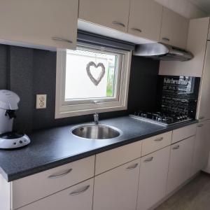 eine Küche mit Spüle und Fenster mit einem Herzaufkleber in der Unterkunft J 062 in Petten