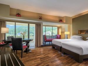 a hotel room with a bed and a desk and a table at Pullman Phuket Karon Beach Resort in Karon Beach +215 photos